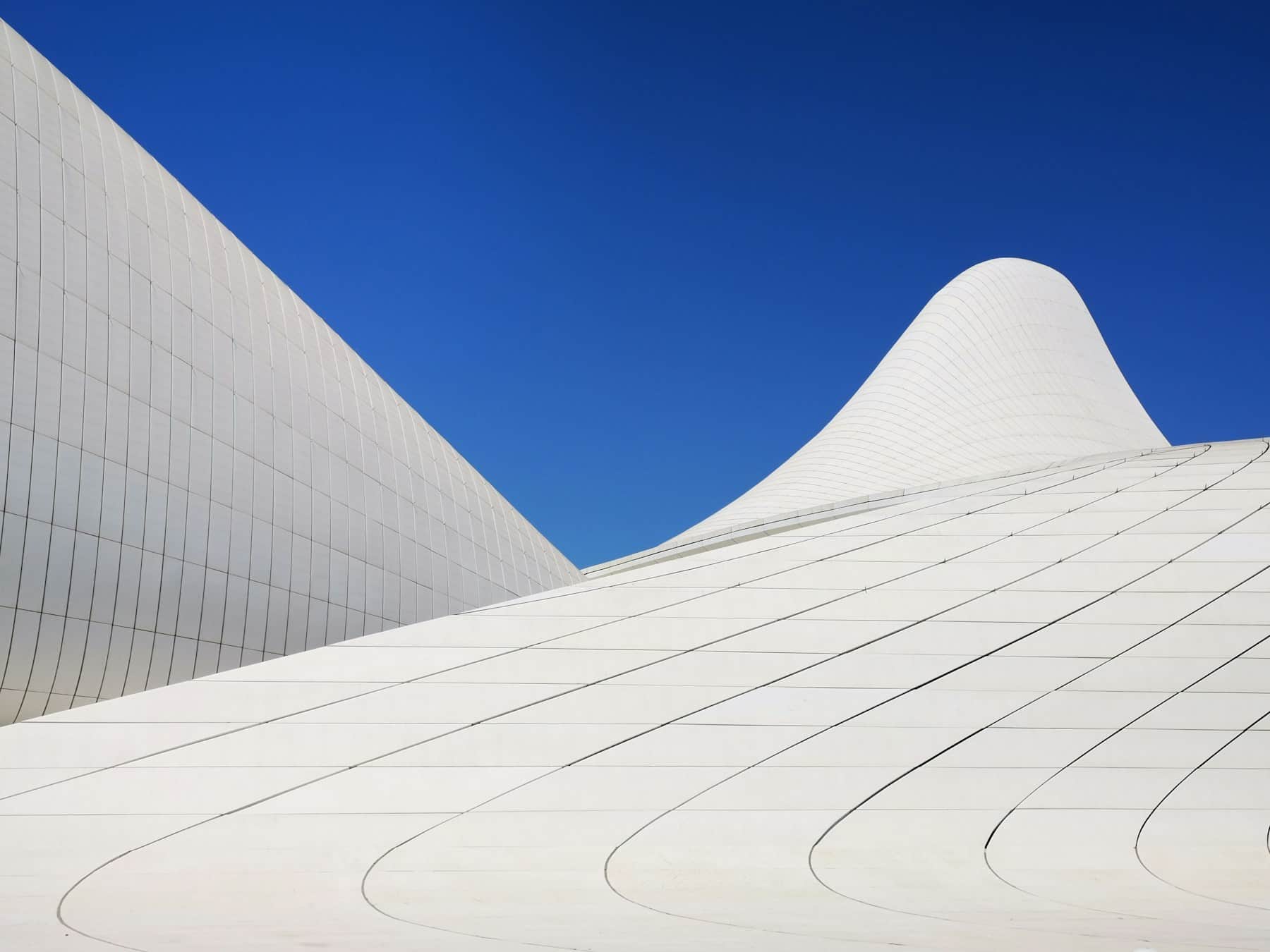 The curved white façade of a contemporary building in Baku against a clear sky